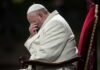 Pope sitting with his head bowed and hand covering his face