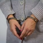 A person wearing handcuffs with their hands clasped together