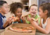 Children happily eating pizza together.
