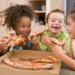 Children happily eating pizza together.