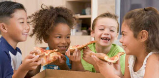 Children happily eating pizza together.
