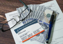 Stolen IDs Fuel $600M Hospice Scam! Medicare card glasses pen money on wooden table