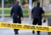 Police officers walking past caution tape at a crime scene