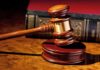 A wooden gavel resting on a polished surface with a law book in the background