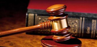A wooden gavel resting on a polished surface with a law book in the background