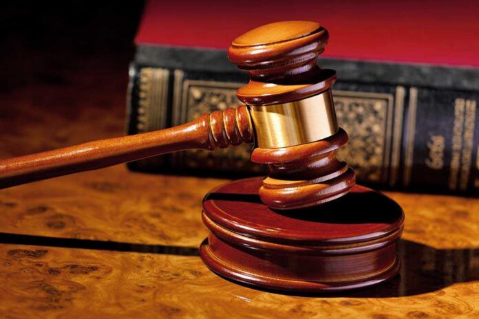 The,Judge,Hammer,A,Judge,In,Court.,Located,On,A A wooden gavel resting on a polished surface with a law book in the background