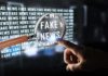 Poll Shocker: Media Rhetoric or Shooter to Blame? A hand pointing at the words 'FAKE NEWS' magnified by a glass