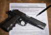 Gun Rush Erupts Before July 1st Ban Gun and pen on firearm transaction form.