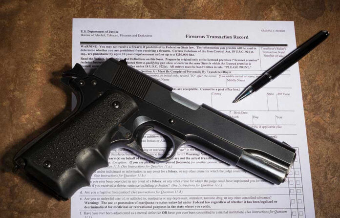 1026045637 Gun and pen on firearm transaction form.