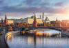 Kremlin by river at sunset with bridge.