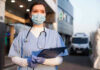 Hospital Nightmare: Fake Nurses Slip Through Nurse in scrubs and mask outside hospital holding clipboard.