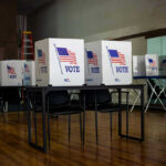 Feds Raid Voter Rolls — Why Now? Voting booths set up in a room.