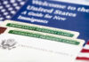 Citizenship Crackdown EXPLODES — Who’s Next? Permanent resident cards with welcome guide and flag.