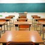 Child Meals Scam — Fugitive Nabbed Abroad Empty classroom with desks and a chalkboard.
