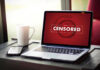DNA Heist Sparks $46.8M Payout Laptop screen displaying CENSORED beside coffee and phone