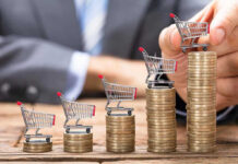 Inflation Spike Slams May — 3-Year High Mini shopping carts on stacks of coins, business background.