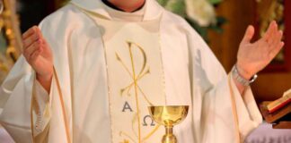 A priest holding a golden chalice during a religious ceremony