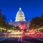 Trump Threatens Federal Takeover Of D.C. The U.S. Capitol building illuminated at night with city traffic in the foreground