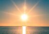 A serene sunrise over a calm ocean with vibrant colors in the sky