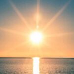 Heatwave Horror: France’s Deadly Rush To Water A serene sunrise over a calm ocean with vibrant colors in the sky