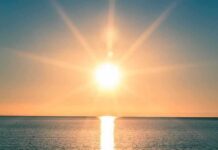 A serene sunrise over a calm ocean with vibrant colors in the sky