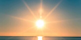 A serene sunrise over a calm ocean with vibrant colors in the sky