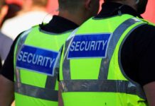 Two security personnel wearing high visibility vests with SECURITY printed on the back