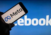 Meta on phone screen, Facebook in background.