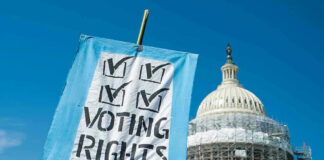 Sign reading Voting Rights in front of Capitol building.