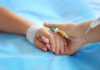 ER Chaos Isn’t What You Think Two hands holding, one with medical IV attached.