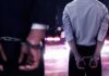 Extradition Twist: Tate Brothers Face 59 Counts Two men in handcuffs with police lights in the background