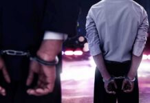 Extradition Twist: Tate Brothers Face 59 Counts Two men in handcuffs with police lights in the background