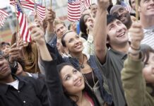 A diverse group of people joyfully waving American flags in celebration