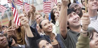 A diverse group of people joyfully waving American flags in celebration