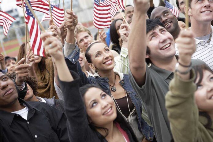 A diverse group of people joyfully waving American flags in celebration