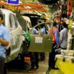 BMW’s Silent Axe Targets Desks auto assembly line with workers installing car doors