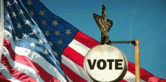 A vintage Vote sign in front of an American flag