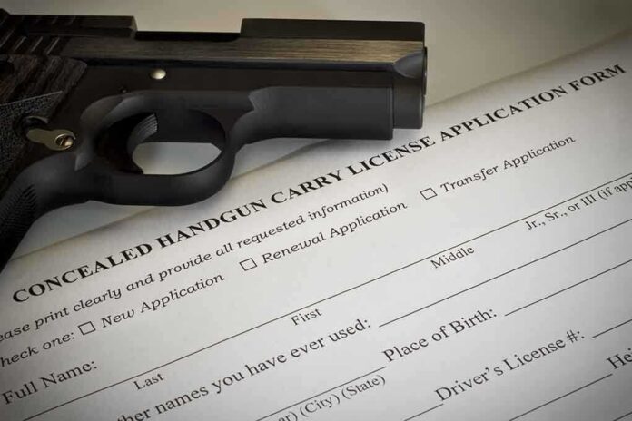 shutterstock_200097830 A handgun placed on top of a concealed carry license application form