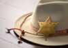 Wild ‘Immunity’ Plea After Sheriff Threat A sheriffs hat with a vintage badge resting on a wooden surface