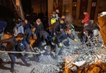 Rescue workers search through rubble at night