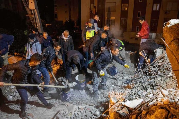 Rescue workers search through rubble at night