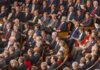 Audience of formally dressed people seated in a large auditorium