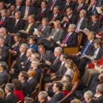 Communist Wave Inside Democrats? Audience of formally dressed people seated in a large auditorium