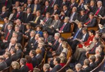 Communist Wave Inside Democrats? Audience of formally dressed people seated in a large auditorium