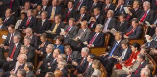 Audience of formally dressed people seated in a large auditorium