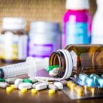 Pulmonary Infarction—Fauci’s Quiet Crisis? Medicine pills and syringe on table with brown bottle