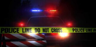 Police car behind crime scene tape at night