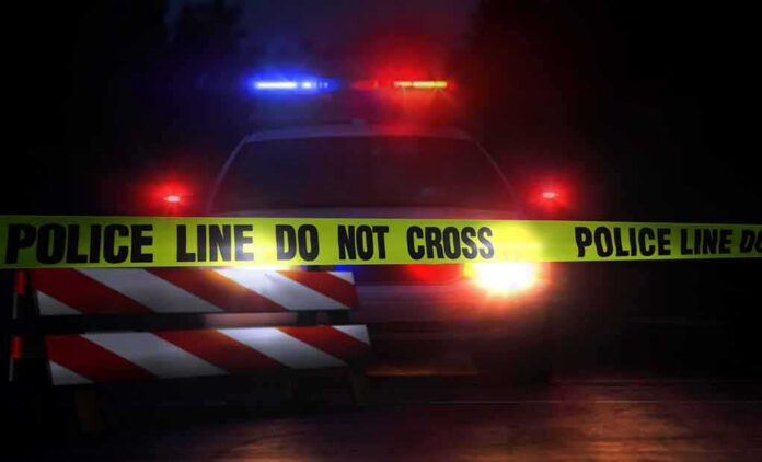 shutterstock_693454099 Police car behind crime scene tape at night