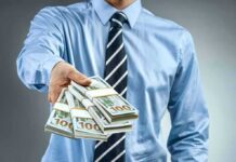 Person in business attire offering bundles of US dollar bills