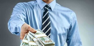 Person in business attire offering bundles of US dollar bills